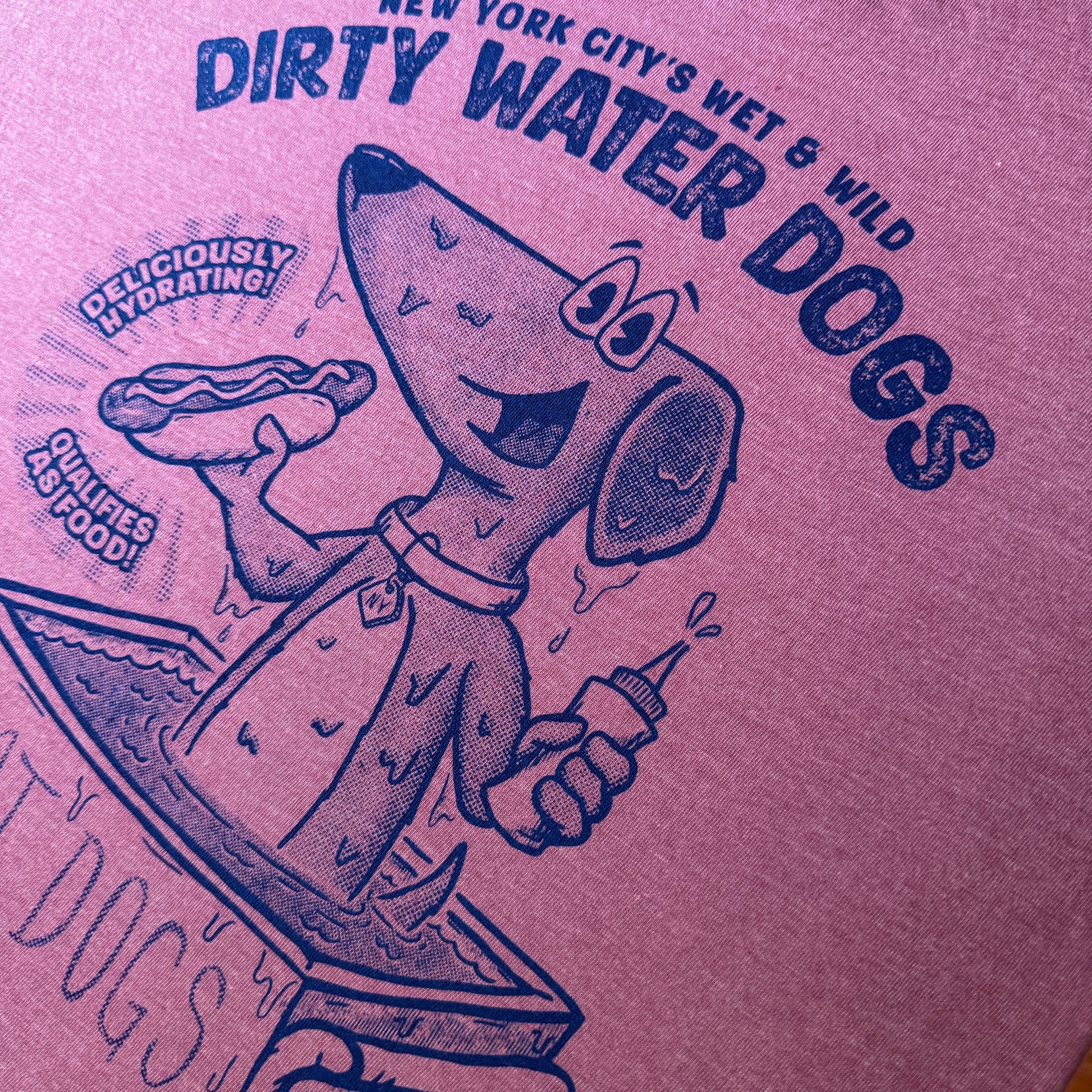 Purple t-shirt with blue graphic and text 'Dirty Water Dogs' on a wooden surface.