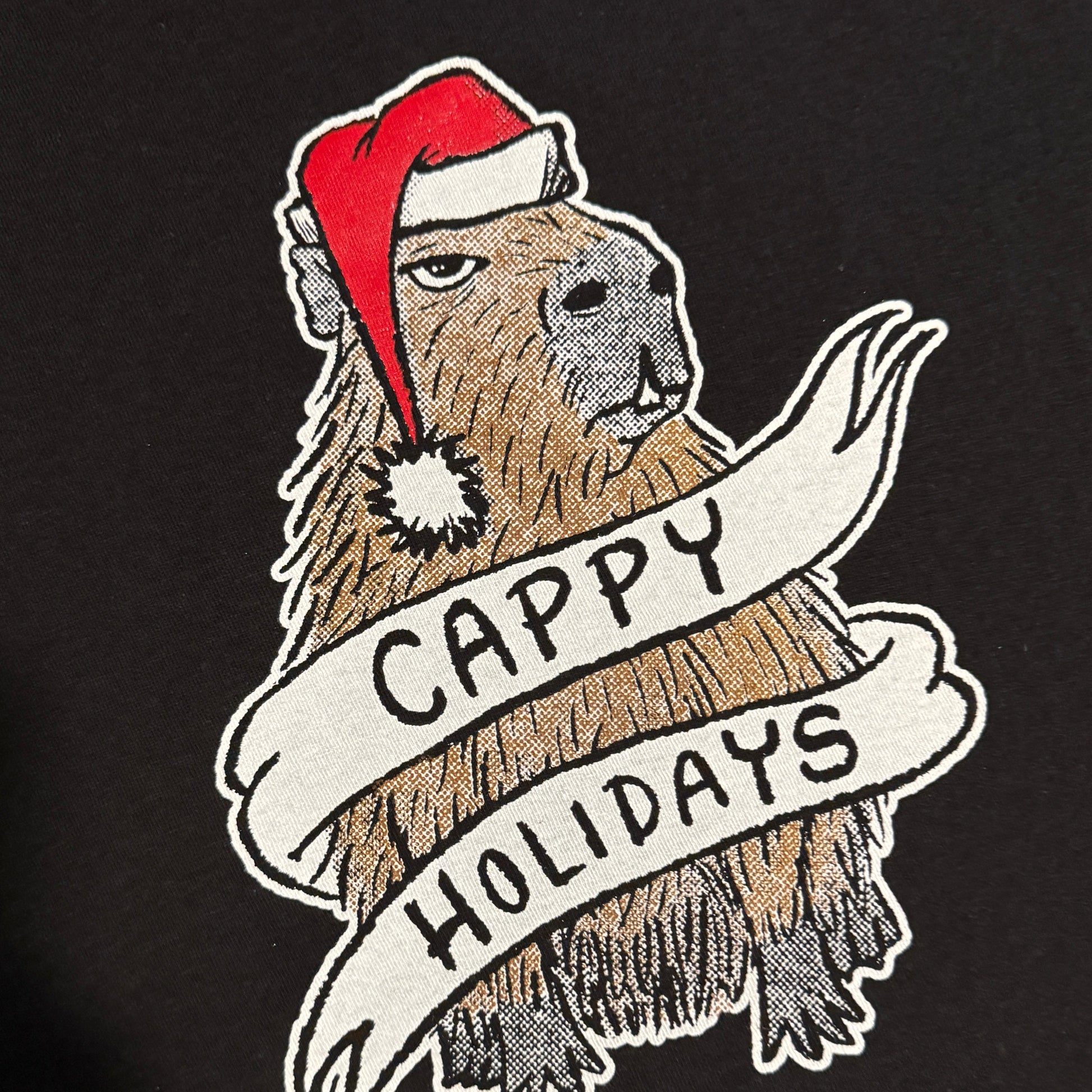 Dark green t-shirt with a graphic of a capybara wearing a Santa hat and a banner reading 'Cappy Holidays'.