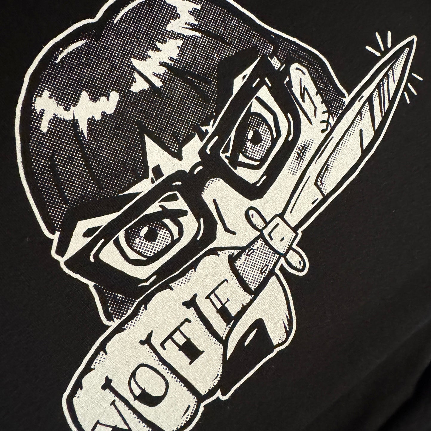 Black t-shirt with white graphic design of a girl with glasses holding a knife and text on a black background