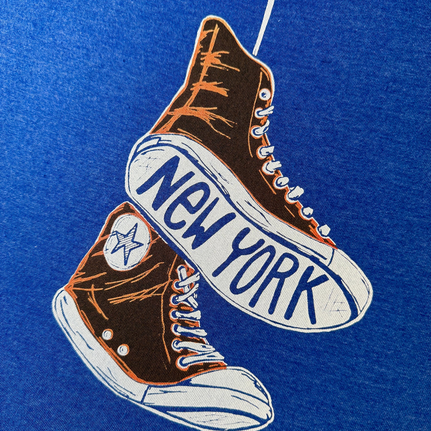 New York Knicks colored Orange high-top sneakers with 'New York' text on a blue t shirt
