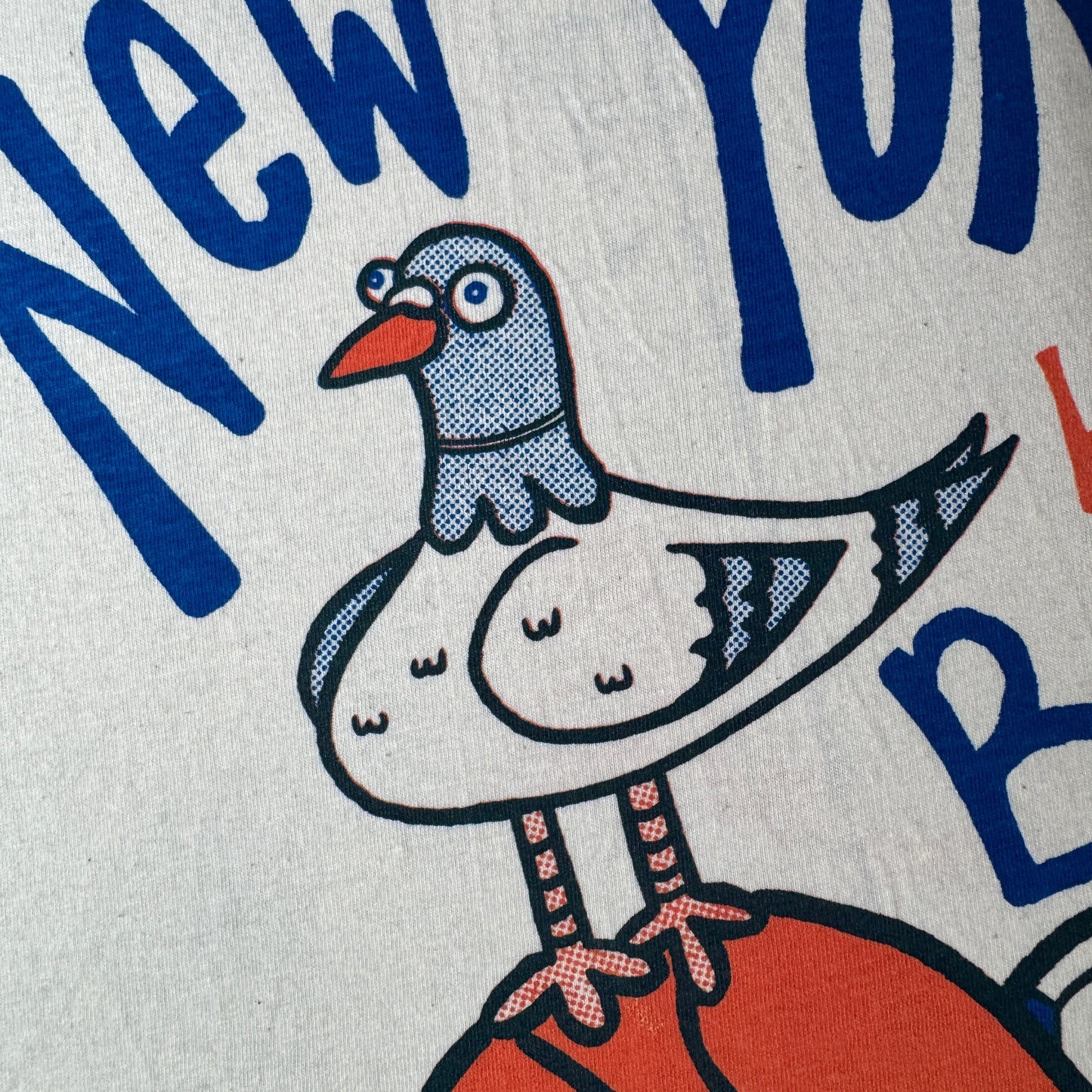 T-shirt with 'New York Has Balls' text and a pigeon with sports ball graphics on a vintage white shirt