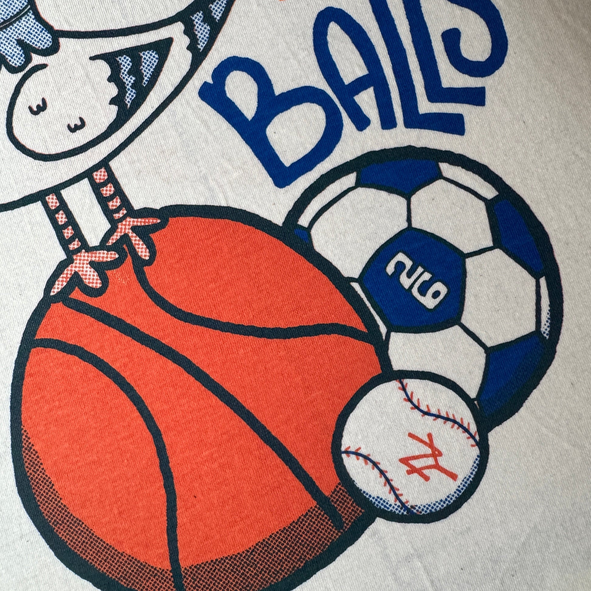 T-shirt with 'New York Has Balls' text and a pigeon with sports ball graphics on a vintage white shirt