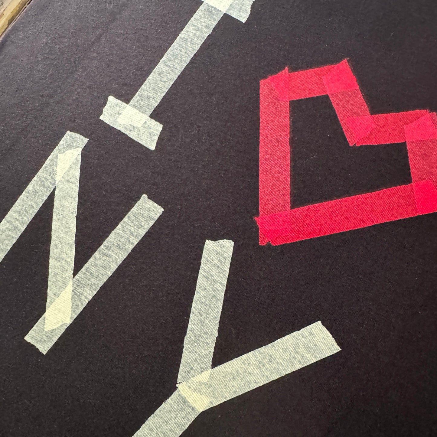 Close up of a I masking tape heart NY printed black t-shirt