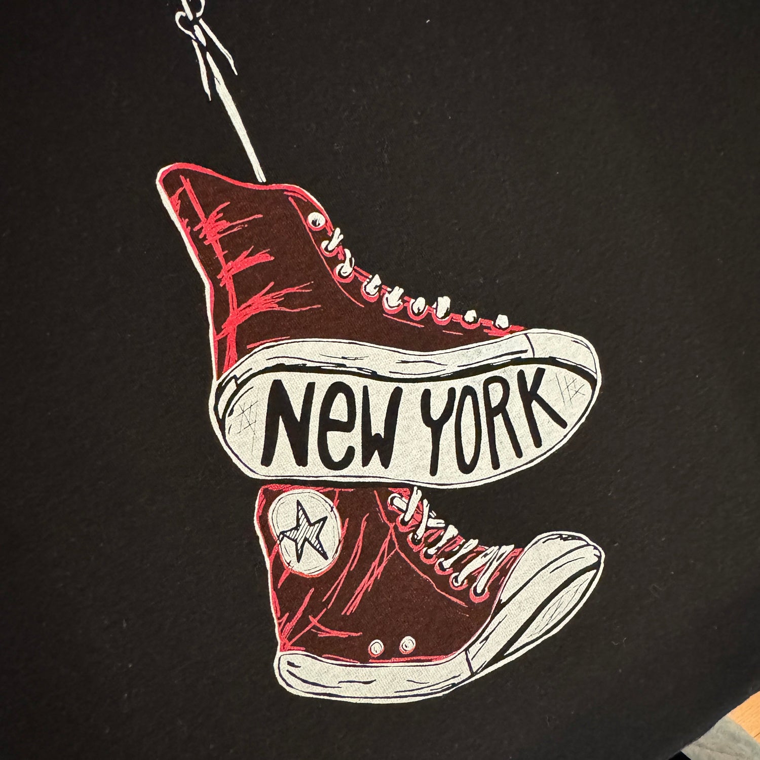 Black shirt with white and red graphic of sneakers and 'New York' text on the sole
